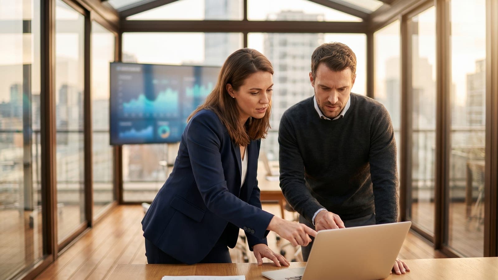 Two colleagues carefully reviewing a suspicious email on a laptop in an office.